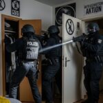 Cops bei Razzia, einer zielt mit Waffe auf Arsch des anderen