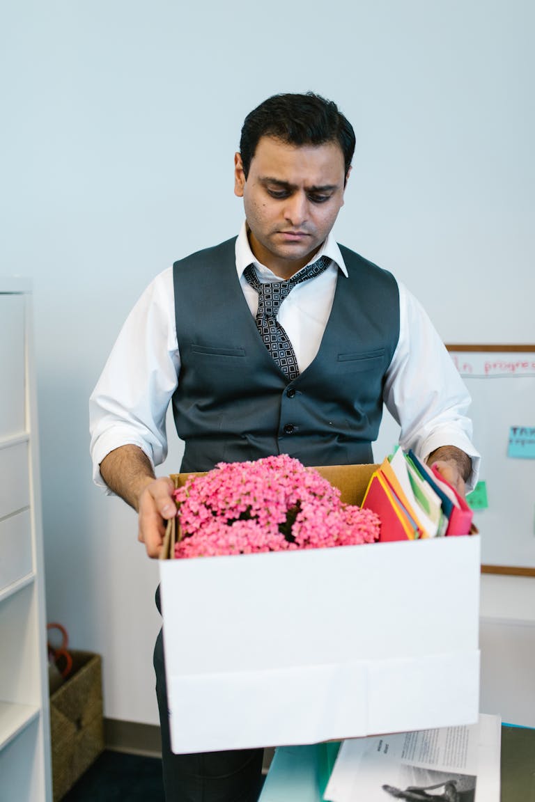 Businessman packing personal items in office after job termination.