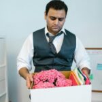Businessman packing personal items in office after job termination.
