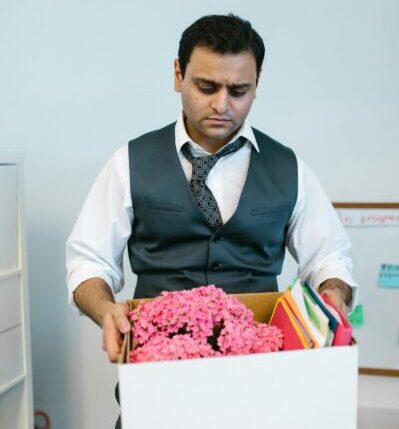Businessman packing personal items in office after job termination.